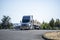 Powerful gray big rig semi truck with loaded by lumber flat bed semi trailer standing on the industrial parking lot take a break