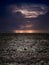 Powerful lightnings in dark stormy sky above plowed farm field