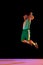 Powerful moment frozen in time, basketball player commitment to perfect slam dunk against black background in neon light