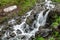 A powerful mountain stream flows down from the rocks in a dense fog