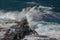 Powerful ocean wave breaks against a rocky shoreline on a sunny day