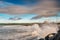 Powerful ocean wave crushes on stone shore. West coast of Ireland, Lahinch town, county Clare. Warm sunny with cloudy sky,