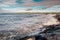 Powerful ocean wave crushes on stone shore. West coast of Ireland, Lahinch town, county Clare. Warm sunny with cloudy sky,