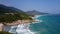 Powerful ocean waves roll on beach clutched among rocks