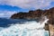 Powerful sea surf breaks the water on the rocky shore near the lighthouse. Seascape