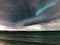 Powerful storm brewing over a serene ocean, with huge waves crashing onto the shoreline