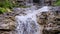 Powerful stream of clean water quickly flows down from mountains, spray of waterfall scatters from stones, concept of wild nature