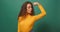 Powerful strong woman flexes arm muscle, winks smiles, greens studio background