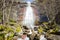 Powerful, sunlit waterfall streaming down the red cliff