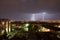Powerful thunderbolt hits the city at night. A strong lightning strike over a dark gray sky hits the ground