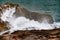 Powerful waves crash against rugged boulders and stones, creating dynamic spectacle of nature raw force. tumultuous sea surges,