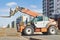 Powerful wheel forklift with telescopic mast at the construction site of a modern residential area. Construction equipment for