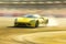 A powerful yellow sports car drifting around a track with the sunlight reflecting off its body. Speed drive concept. AI