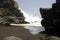 Powerfull waves crashing on a rock and splashing water in the air on remote black lava sand beach at Pacific coast