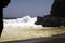 Powerfull waves crashing on a rock and splashing water in the air on remote black lava sand beach at Pacific coastline