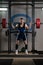 Powerlifter Using Barbell Exercising Legs Inside Gym