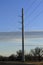 A Powerline metal pole with cables and blue sky with clouds and trees