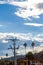 Powerline and pole with palm trees and construction, against hillside