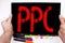 PPC - Pay per Click text written on tablet, computer in the office with marker, pen, stationery. Business concept for Internet SEO