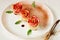 Ðpple rose tarts on the white plate decorated mint leaves and cinnamon powder. Vegetarian autumn dessert on the white background