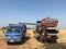 Prachinburi Thailand 4 December 2020: blue and orange combine harvester of rice and trailer on the farmland in harvest season