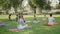 Practitioners doing head bends together with yoga instructor in sunny park