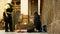 PRAGUE, CZECH REPUBLIC, SEPTEMBER 9, 2019: Homeless girl begging tourists throw coin money into cap, a police officer