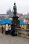 Prague. Sculpture of John of Nepomuk on Charles Bridge. Beggar near tourists.