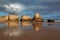 Praia dos Tres Castelosn in Portimao, Portugal. Rocks and clouds reflect in the low tide water