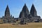 Prambanan Temples with stone ruins and tourists carrying umbrella leaving & entering the complex