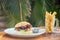 Prawns burger and french fry on table tropical sea ,palms tree and beach background