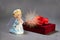 Praying angel and gift box with red ribbon and light.