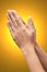 Praying hand sign, two woman`s palm are clasped all together. Isolated on yellow background. hand language concept