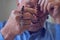 Praying hands of an old man holding rosary beads.