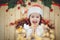 Praying little girl with a festive garland on wooden background.