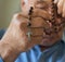 Praying old man with hands holding rosary beads.