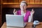 Praying! Portrait of wishful attractive young girl freelancer in pink t-shirt is sitting in cafe and working on laptop, closed