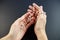 Praying on the rose garden, the hands of a young virgin with a rosary close-up on a black background