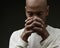 praying to god Caribbean man praying on black background with people stock image sock photo