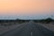 Pre dawn light in desert sky with empty road, passing through the desert. Wind mills in the horizon, Thar desert, Rajasthan, India