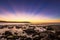 Pre dawn sun rays over ocean and rocky coastline