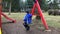 Pre-school age boy on swing in the park from behind. Young boy playing alone on swing in playground in winter.