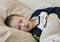 Pre-school sick boy with closed eyes lying in bed with a digital thermometer