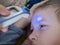 Pre-school sick boy lying on pillow in bed. Mother is measuring body temperature on his forehead with modern digital thermometer