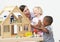 Pre-School Teacher And Pupils Playing With Wooden House