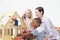 Pre-School Teacher And Pupils Playing With Wooden House