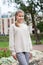 Pre-teen Caucasian girl wearing beige blouse and grey breeches standing outdoor, posing for camera