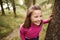 Pre-teen girl taking a break leaning on tree during a hike in a forest, elevated view, close up