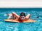 Pre-teens play in the pool by jumping on a small surfboard to keep their balance