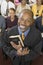 Preacher Holding Holy Bible With Congregation Sitting In Church